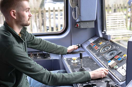 A train driver in the commuter cabin operating the controls, Tarka Valley Railway, Devon UK.