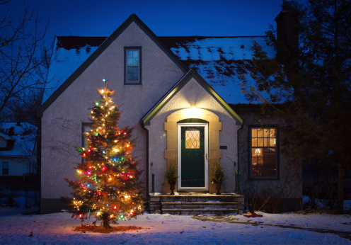 Subject: An outdoor Christmas tree decorated with lights and ornament in front of a residential home.