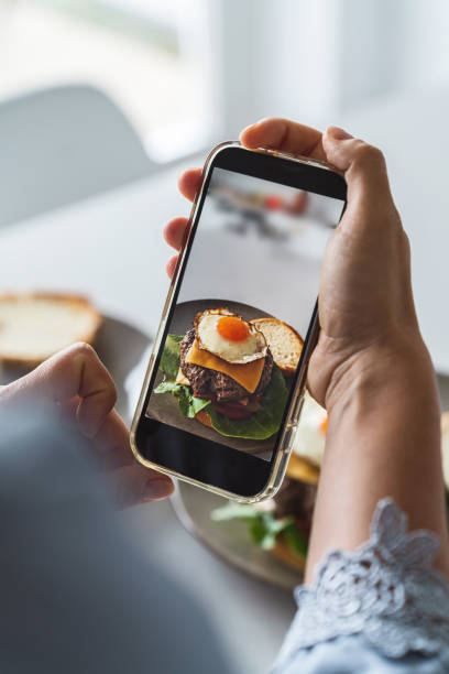istock Female hands using a smartphone to photograph a delectable homemade cheeseburger with a fried egg on top 1713330372