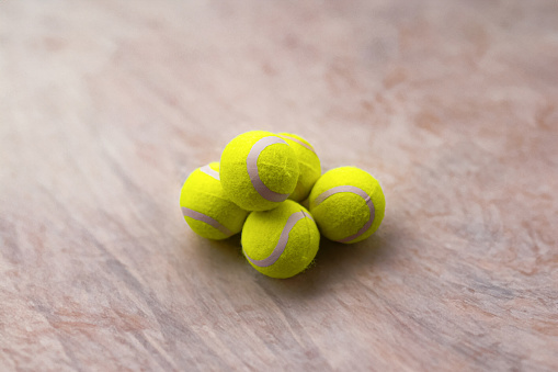 Close-up image of tennis balls stacked on the floor of a practice tennis court.