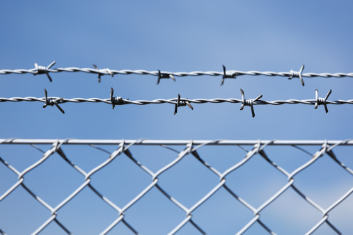 Barbed wire. Blue sky and white clouds.