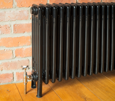 Detail of an old fashioned / retro radiator against a brick wall.