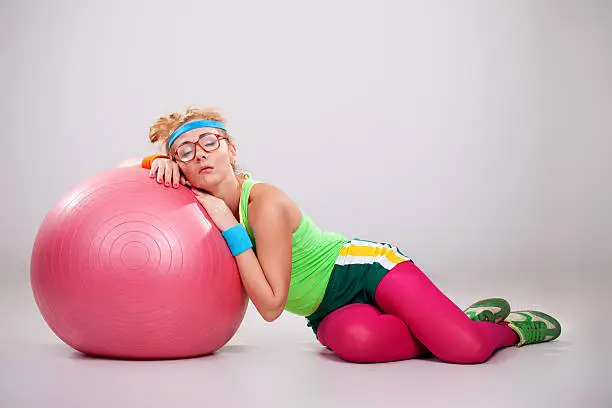 Photo of Tired nerdy fitness girl sleeping on pilates ball