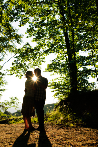 young couple silhouettes kissing at sunset.