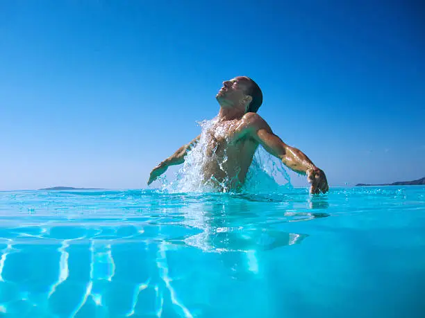 Athletic man emerges with a splash from rippling blue water
