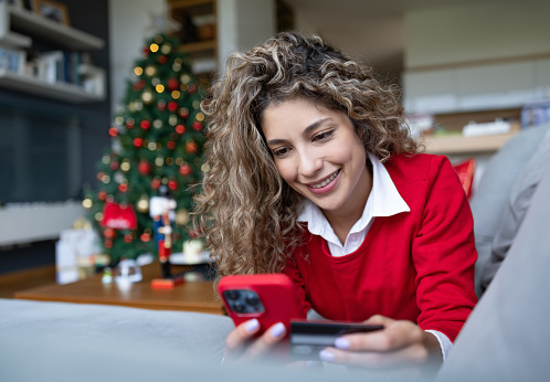 Happy woman buying her Christmas presents from home and paying by credit card - e-commerce concepts