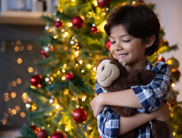 istock Happy boy holding a toy monkey in front of the Christmas tree 1713347806