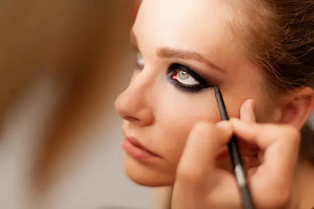 "A model getting her make-up, shallow depth of field, added grain."