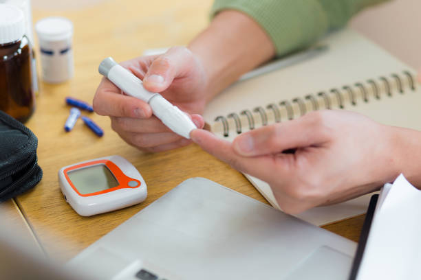 primo piano delle mani dell'uomo usando la lancetta sul dito a casa per controllare il livello di zucchero nel sangue. mani tagliate di glaucometro durante l'esame del test della glicemia a casa. - glaucometer analyzing blood equipment foto e immagini stock