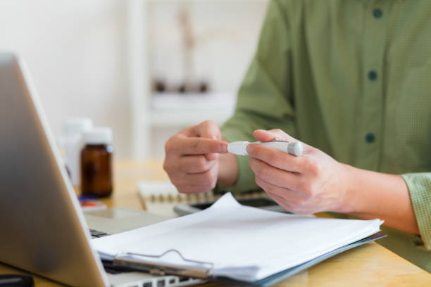 nahaufnahme von männerhänden, die zu hause eine lanzette am finger verwenden, um den blutzuckerspiegel zu überprüfen. abgeschnittene hände des glaukometers bei der untersuchung des blutzuckertests zu hause. - glaucometer analyzing blood equipment stock-fotos und bilder