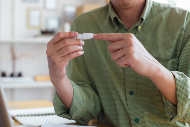 혈당 수치를 확인하기 위해 집에서 손가락에 란셋을 사용하여 남자 손을 닫습니다. 집에서 혈당 검사를 하는 동안 녹내장의 손을 자른다. - diabetes insulin glaucometer human finger 뉴스 사진 이미지