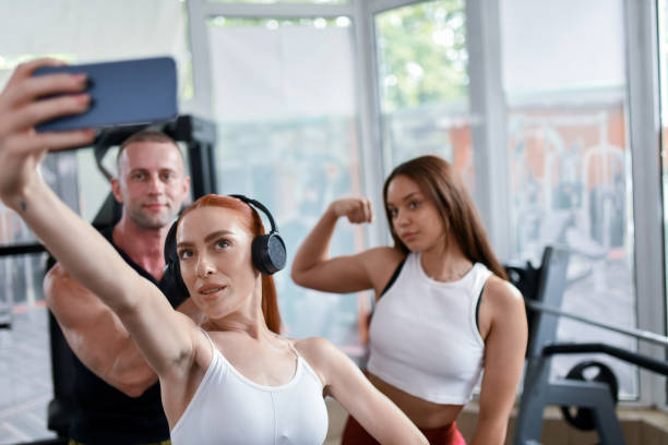 istock Female Athletes Flexing With Fitness Instructor In Gym While Taking Workout Selfie 1713348762