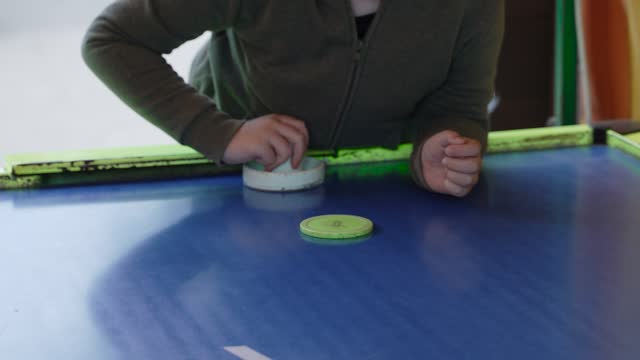 Unrecognizable boy takes air hockey puck with hand, handheld shot. Pushes chip.