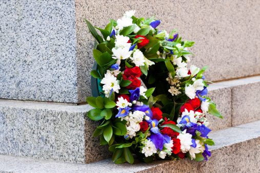 Wreath of red, white and blue flowers against granite stone, full frame horizontal composition with copy space