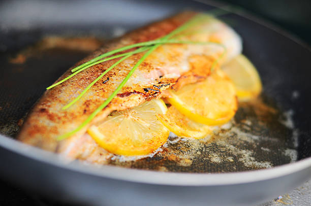Beautiful trout cooking with lemon and fresh herbs.