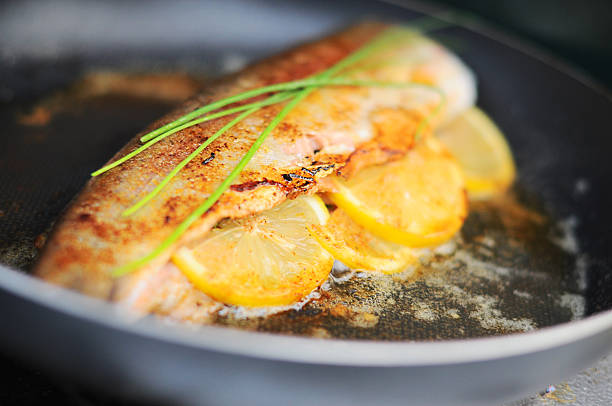 Fresh trout cooking in skillet stock photo