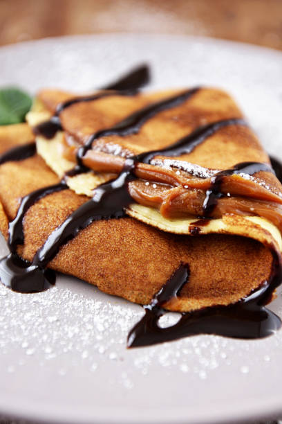 French crepes with caramel fudge on a spoon over stock photo