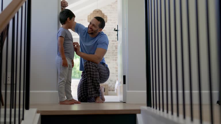 Happy, measuring height and a father with a child writing growth progress on a home wall. Laughing, pride and a dad drawing results of a kid measurement in a house to check for growing together