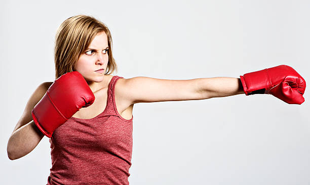 mujer joven muscular grave y punzones al lado de energía - serious punching fighting displeased fotografías e imágenes de stock