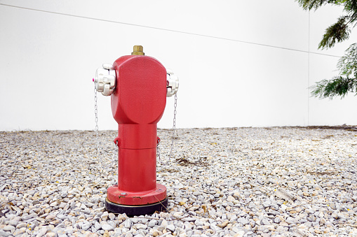 Red metal fire hydrant on the street in an industrial area for fire safety.