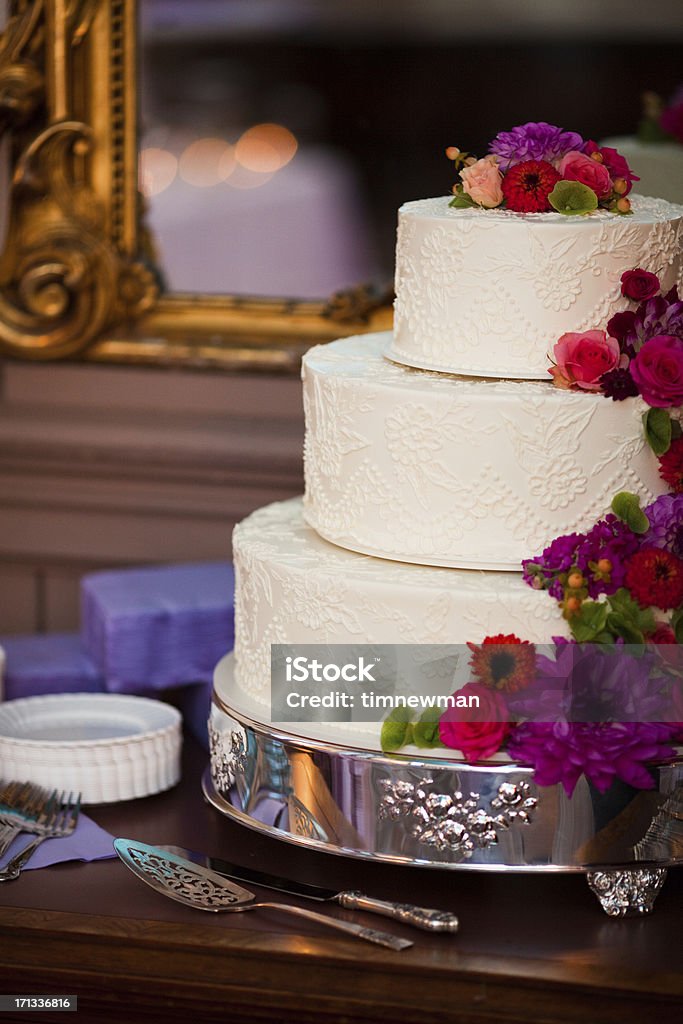 Elegant White Wedding Cake and Floral Arrangement Close Up Detail Beautiful colorful elegant white frosting wedding cake with an elaborate floral arrangement on the cake. Arranging Stock Photo