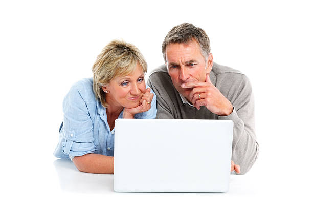 Senior couple lying on floor and using laptop computer Senior couple lying on floor and using laptop computer on white background woman lying on the floor isolated stock pictures, royalty-free photos & images