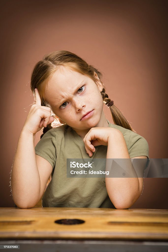 Perplesso giovane ragazza studente seduto alla scrivania - Foto stock royalty-free di 6-7 anni