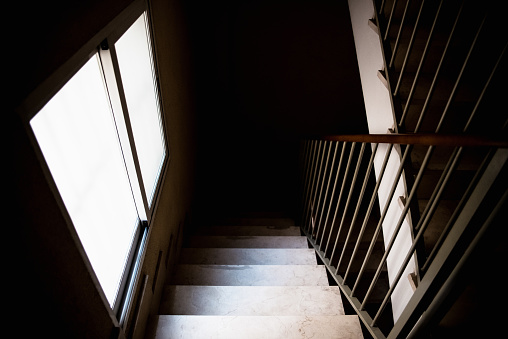 Spooky Dark view of an interior staircase lit by a window, lonely and dangerous.