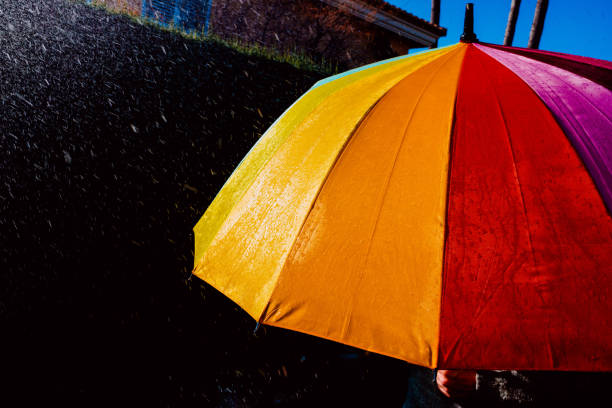 istock Rain on a warm-toned umbrella lit by the sun, isolated on black background with copy space. 1713371806
