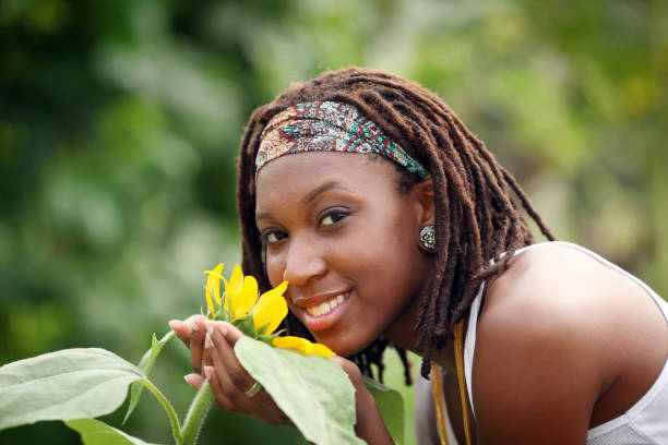 African American teenager embraces a sunflower.