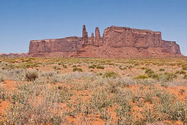 Monument Valley, on the Arizona - Utah border, gives us some of the most iconic and enduring images of the American Southwest. The harsh empty desert is punctuated by many colorful sandstone rock formations. It can be a photographer's dream to capture the ever-changing play of light on the buttes and mesas. Even to the first-time visitor, Monument Valley will probably seem very familiar. This rugged landscape has achieved fame in the movies, advertising and brochures. It has been filmed and photographed countless times over the years. If a movie producer was looking for a landscape that epitomizes the Old West, a better location could not be found. This picture of the Three Sisters and Mitchell Mesa was photographed from the Monument Valley Road north of Kayenta, Arizona, USA.