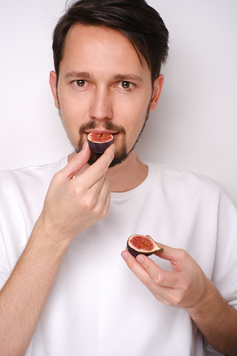 Portrait of a man eating figs on a white background