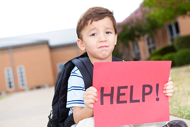 istock Upset young boy at school holding a sign reading HELP! 171339245