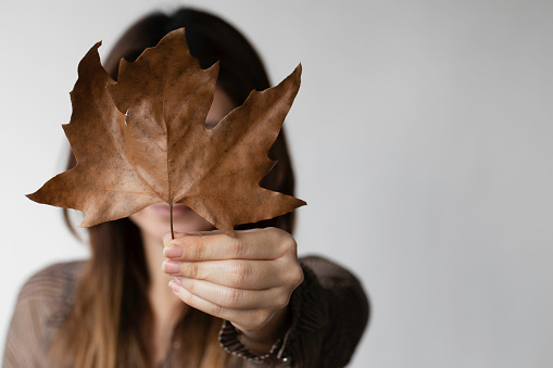 Woman hiding behind a large dry leaf.