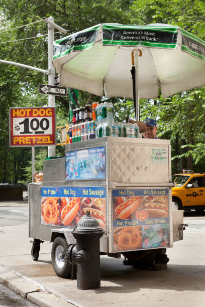 $1 Hot Dog & Pretzel Stand In NYC "New York City, USA - June 20, 2012: A hot dog stand along 5th Avenue by Central Park on the Upper East side of Manhattan with a taxi in the background." hot dog stand stock pictures, royalty-free photos & images