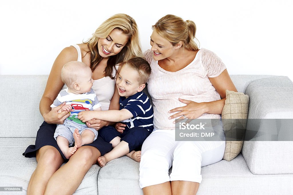 Happy family having fun together Portrait of lesbian couple with their little kids sitting together on sofa having fun Adult Stock Photo