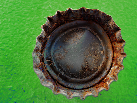 Closeup of old rusty bottle cap bottlecap on green background texture