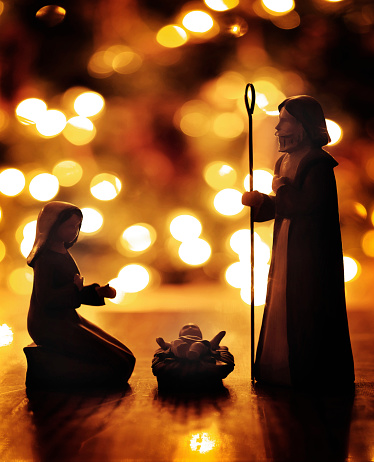 Closeup of Nativity scene with baby Jesus with Christmas lights out of focus for the true meaning of Christian Holiday