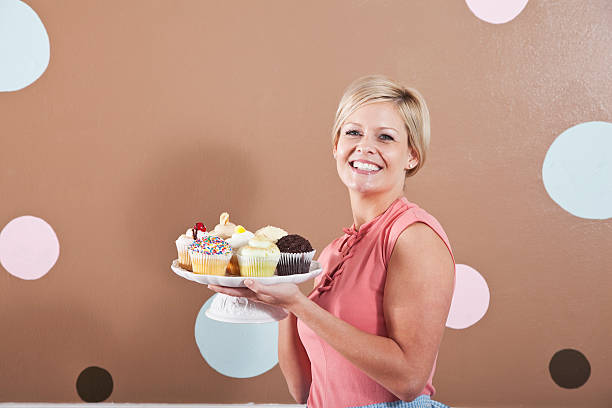 A pretty young woman holding a cupcake and looking away happily