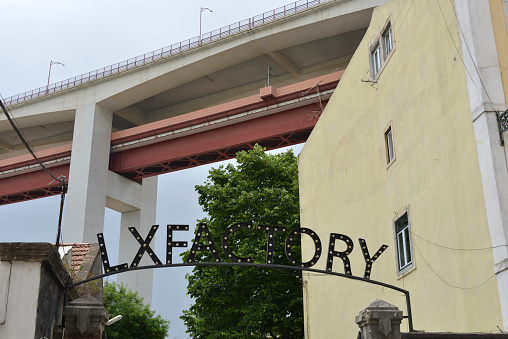 Lisbon, Portugal, 06-15-2022
alternative cultural center LX factory in Lisbon under the Bridge of 25th April at the Tagus river