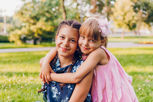 Two little girls enjoy a hug at a picnic in the park.