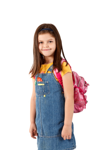 Little girl standing with backpack isolated on white background.