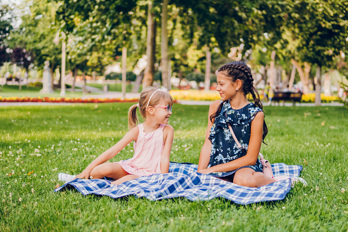 Two little girls enjoy a hug at a picnic in the park.