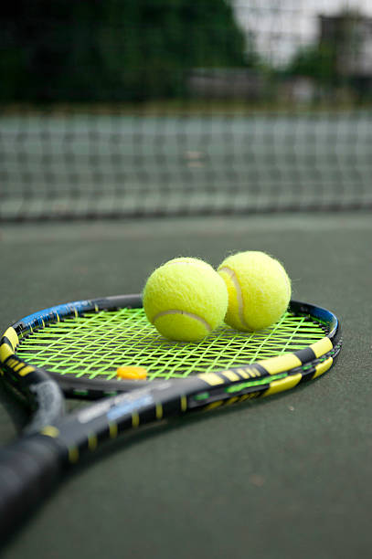 Tennis Racket with two balls on the court stock photo