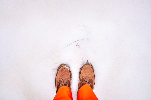Feet of man with shoes standing in front of a snowy field.