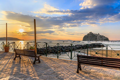 Iconic view of Ischia Ponte from Fisherman's Beach: in the distance Procida Island. Ischia Ponte is a former fishing village and one of the most historic spots on the island.