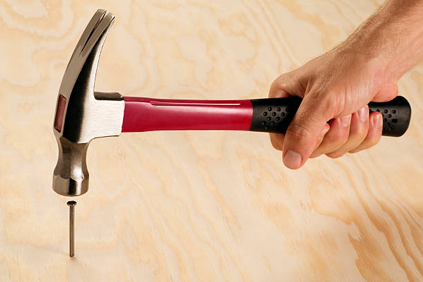 Hitting the Nail on a Head This is a photo of a man hitting the nail on the head. The background is a sheet of plywood. There is a lot of space below for copy.Click on the links below to view lightboxes. hit the nail on the head stock pictures, royalty-free photos & images