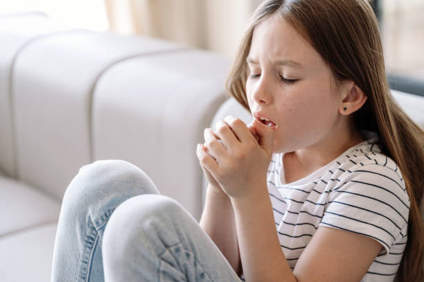 Girl sitting on sofa, feeling bad and suffering from dry cough