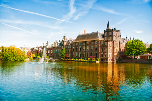 Binnenhof (Dutch Parliament), The Hague (Den Haag), The Netherlands. Visible are Historic buildings, art museum Mauritshuis along the pond Hofvijver, fountain and beautiful cloudscape over the reflection in the water.