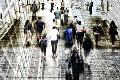 Shot of commuters walking in subway station superimposed over a modern futuristic architecture. The city is NY. High Key.